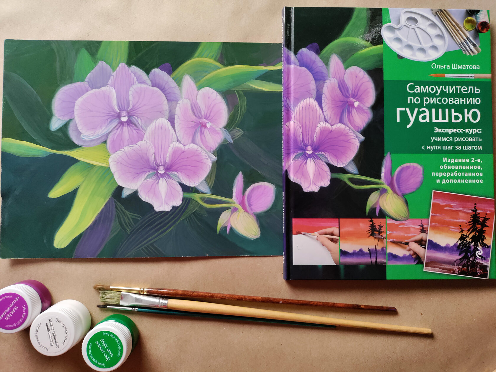 The book beside the orchid painting and jars of gouache